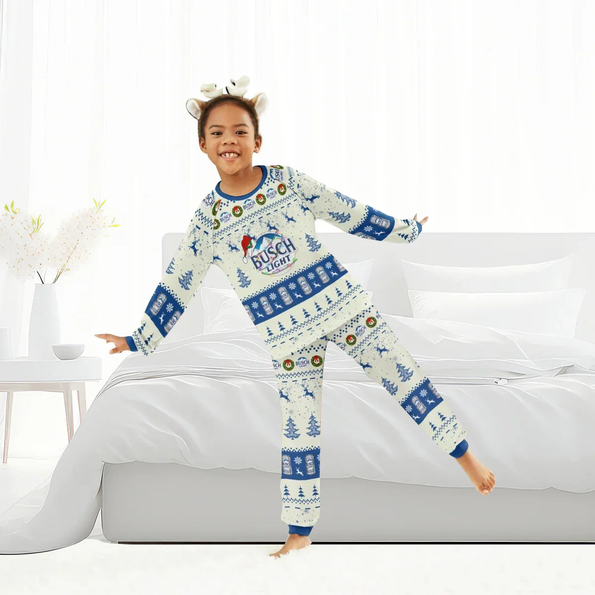Child wearing Busch Light Christmas pajama set with reindeer antler headband in bright bedroom