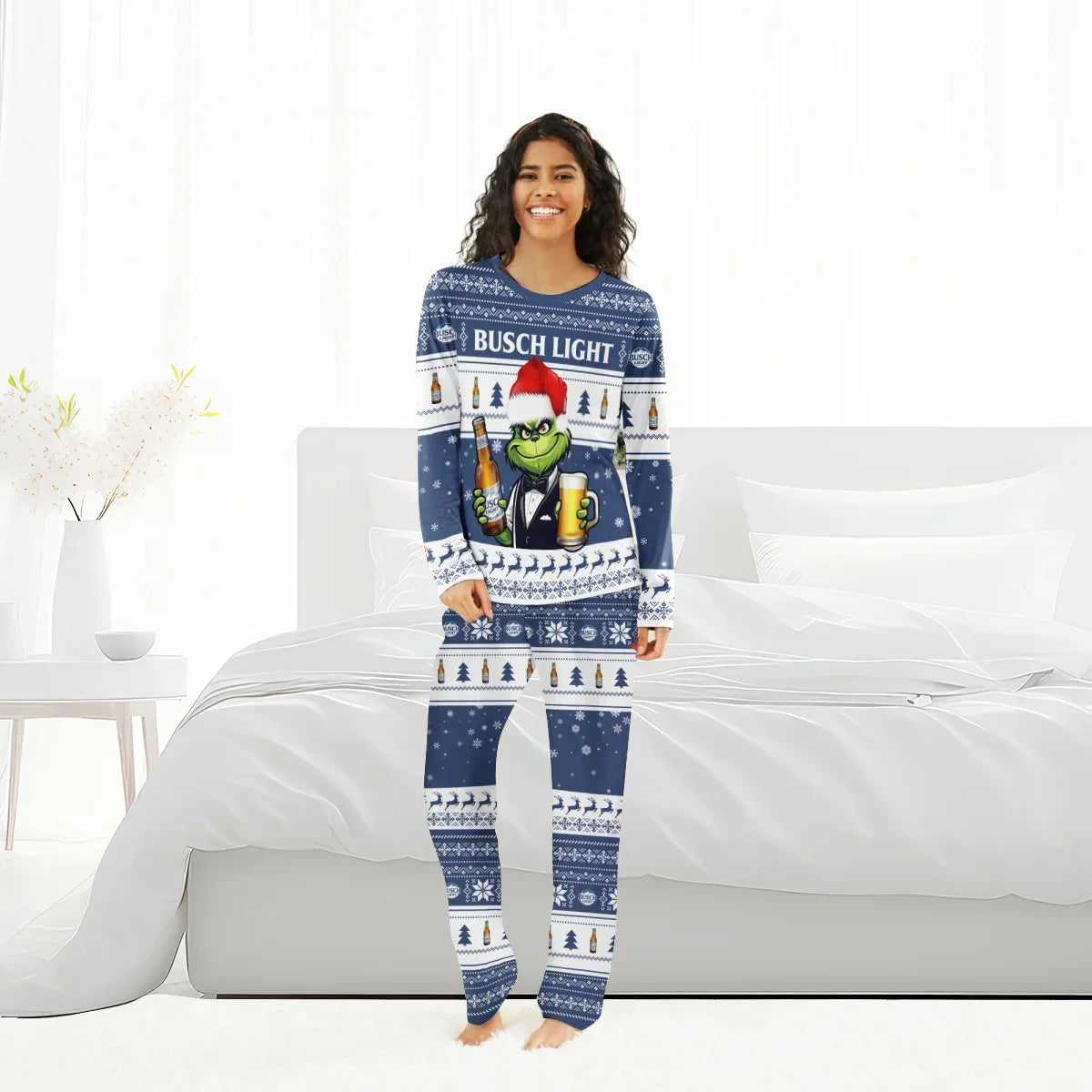 Smiling woman in Busch Light Grinch Christmas pajamas standing in a bright white bedroom