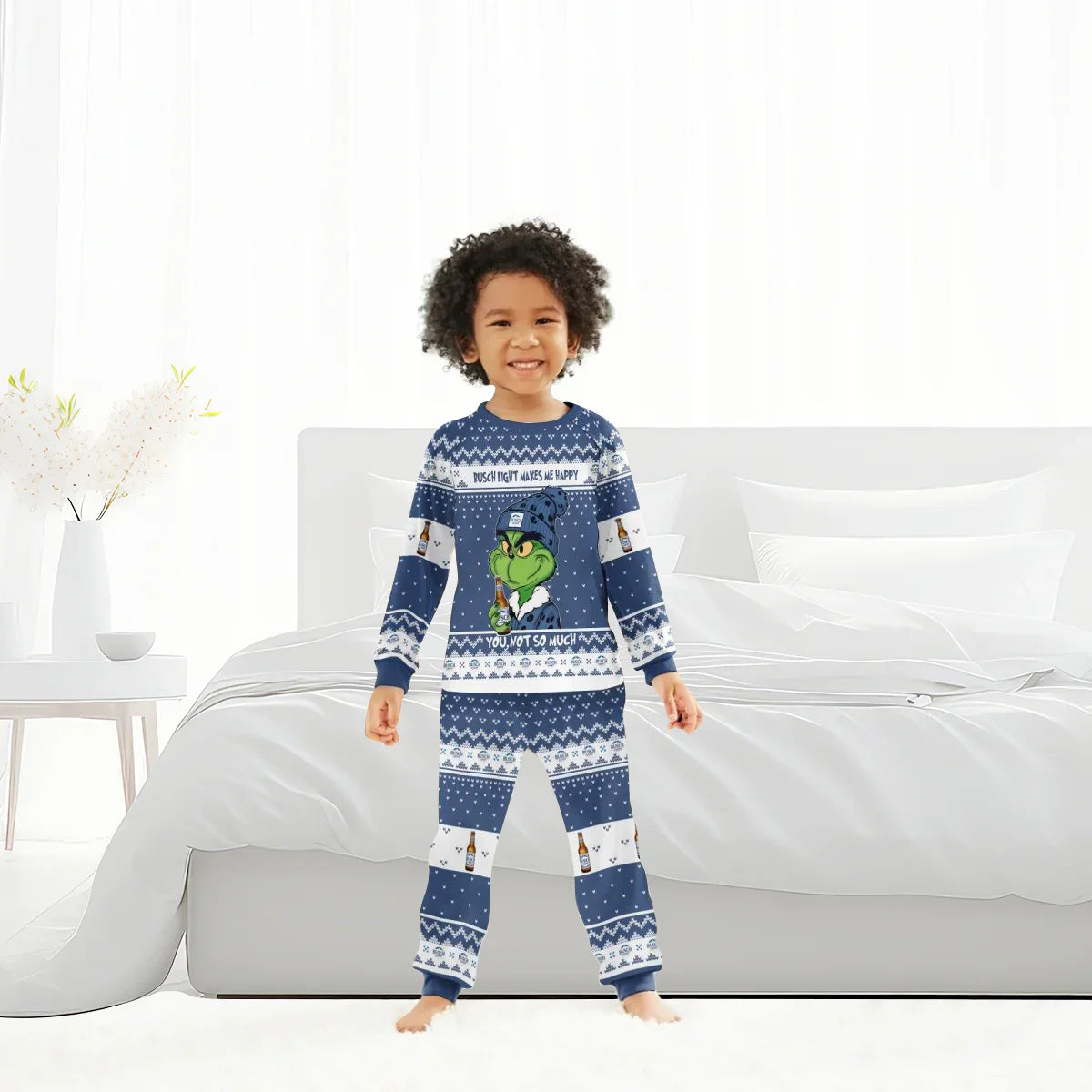 Child in blue holiday pajamas featuring Grinch holding a beer bottle, standing in a bright bedroom