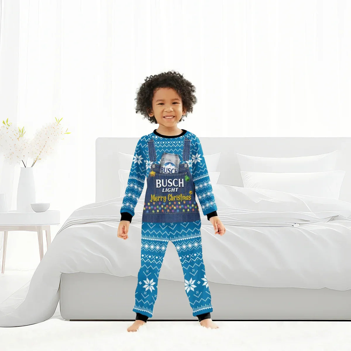 Smiling child wearing blue Busch Light Merry Christmas holiday pajamas standing in modern white bedroom