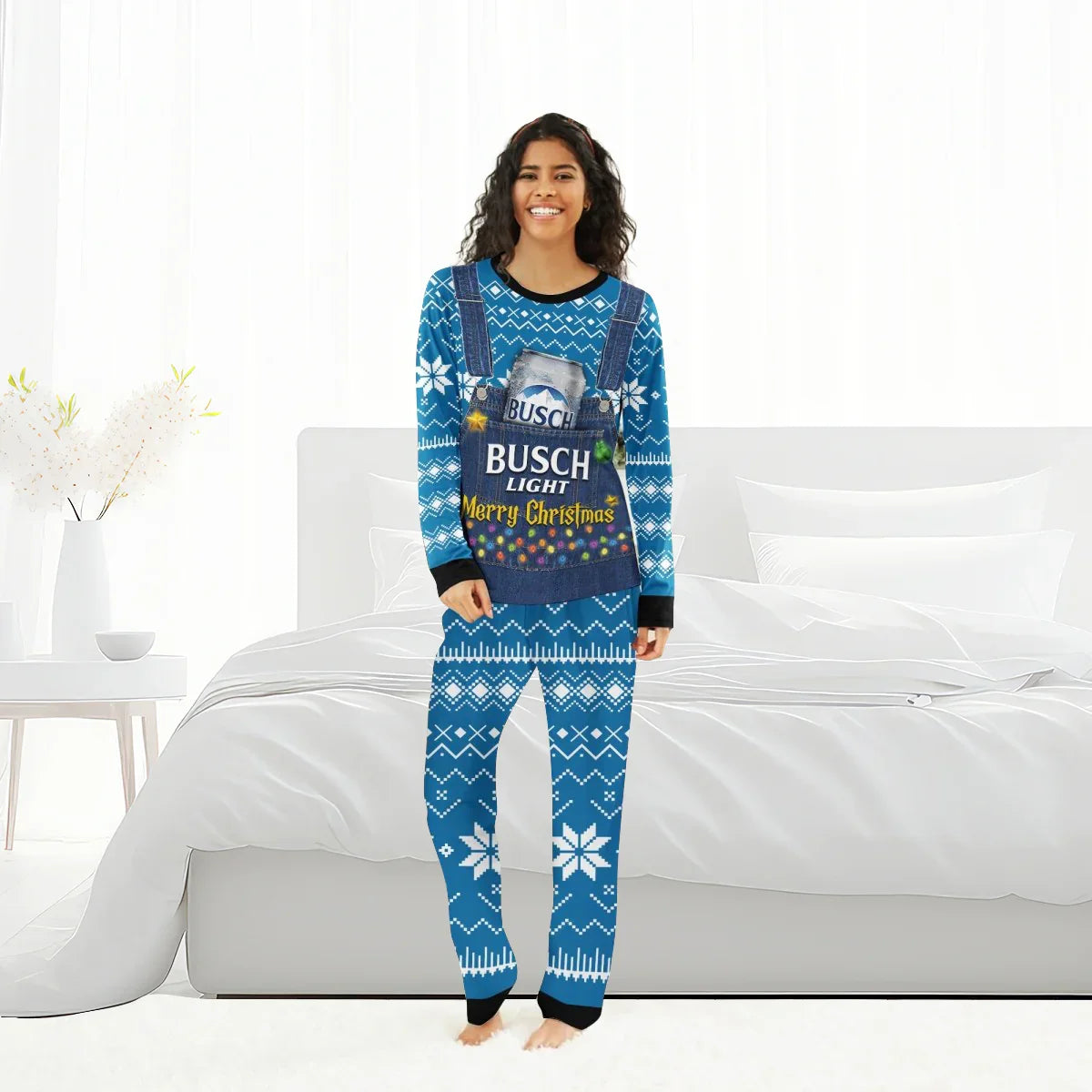 Smiling woman in blue Busch Light Merry Christmas family pajamas with snowflake patterns standing in bright bedroom