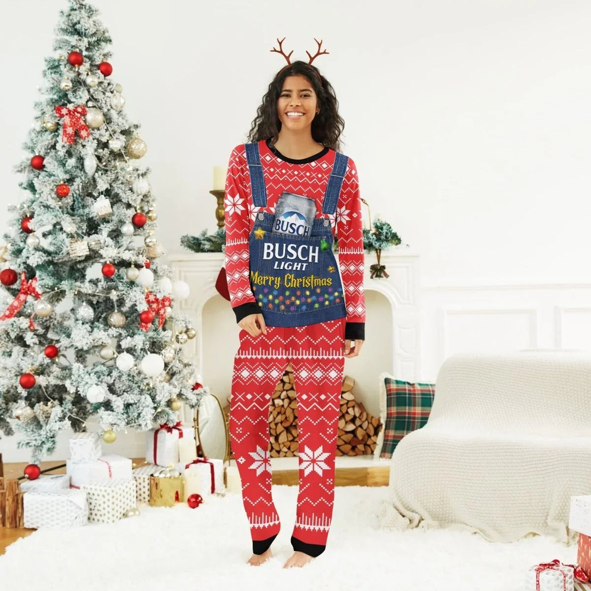 Smiling woman in red Busch Light Christmas pajamas with reindeer antlers standing by decorated tree