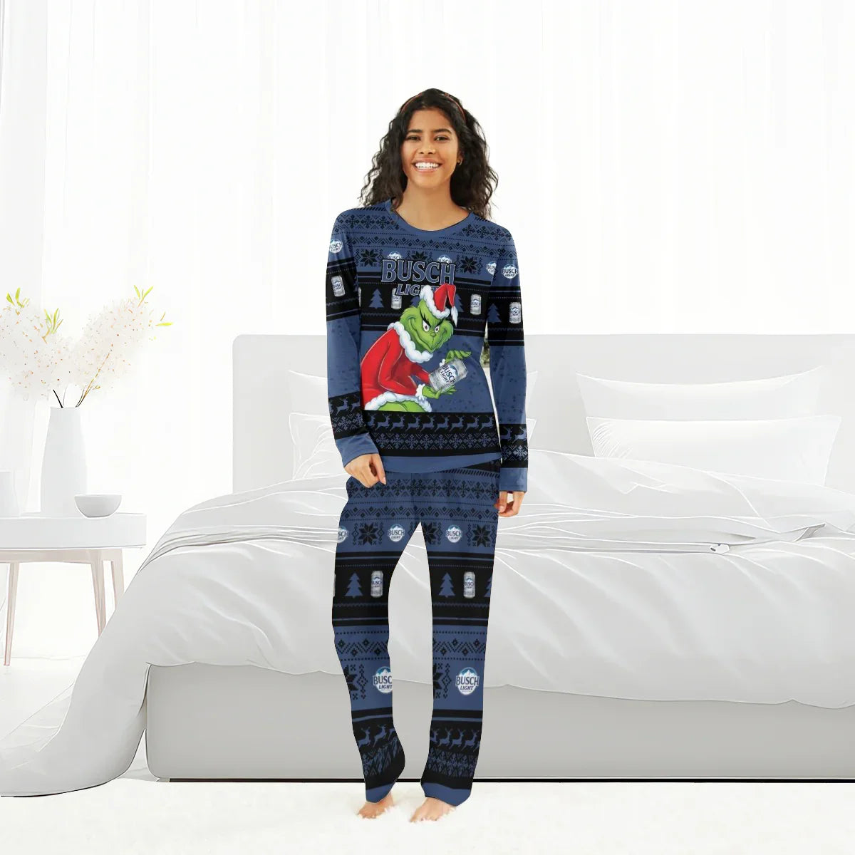 Woman wearing blue Busch Light Grinch Christmas pajama set standing in bright modern bedroom