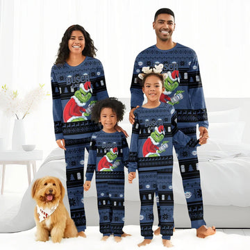Family wearing matching blue Busch Light Grinch Christmas pajamas in a bright cozy bedroom with dog