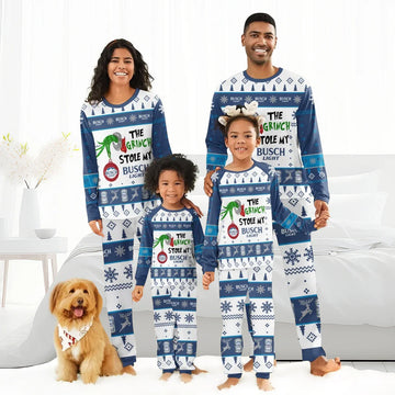 Smiling family in matching blue and white Busch Light Christmas pajamas with Grinch theme, indoors with dog