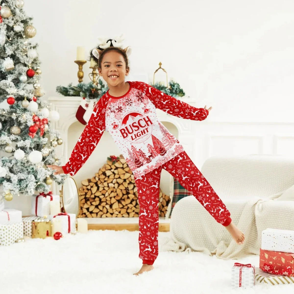 Smiling child in red Busch Light Christmas pajamas posing in festive living room with decorated tree and gifts