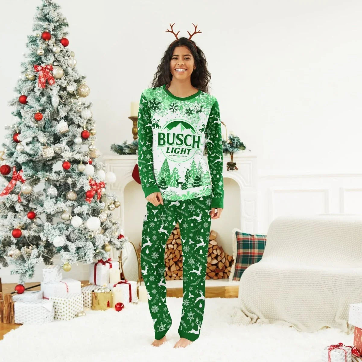 Smiling woman wearing green Busch Light Christmas pajamas with festive reindeer headband in decorated living room