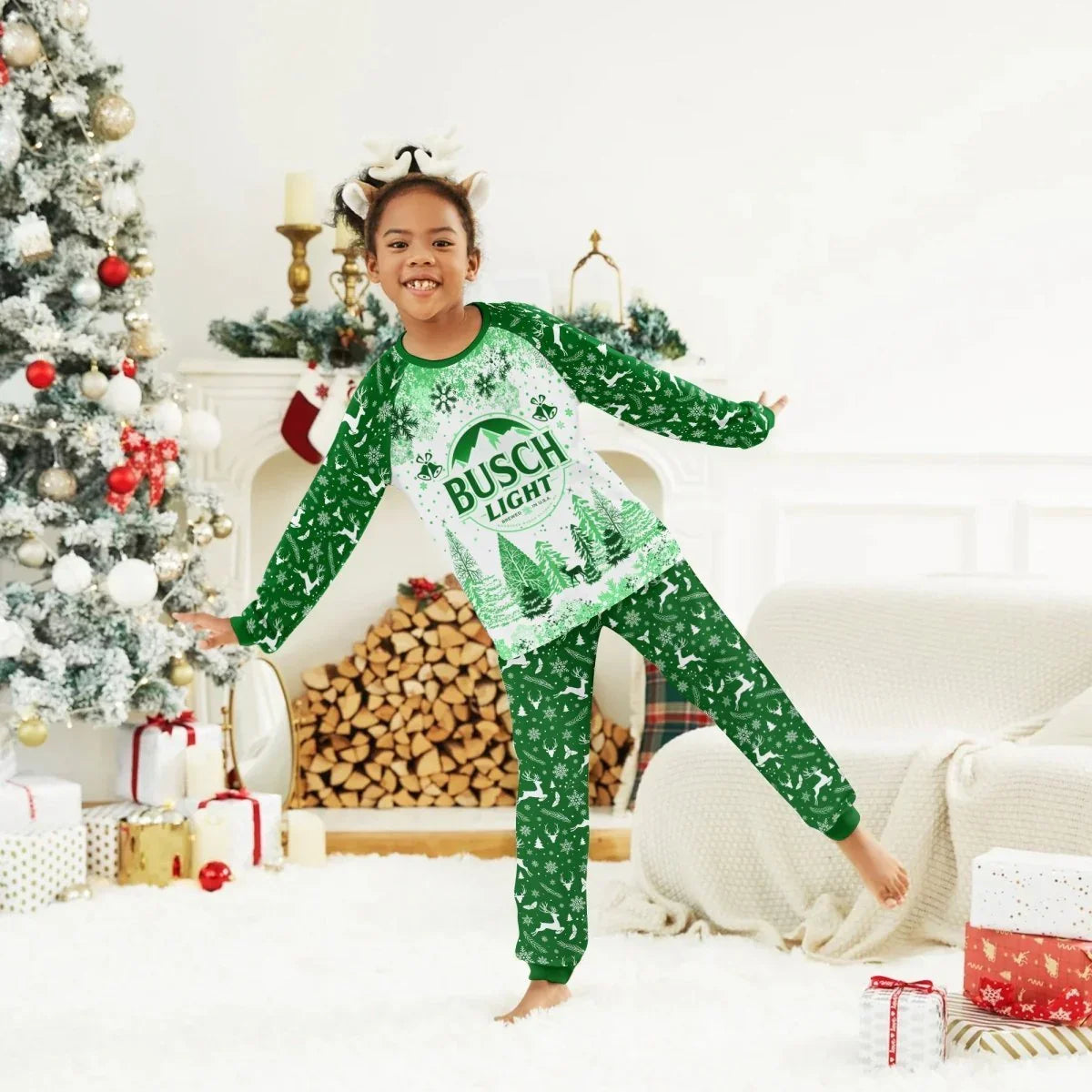 Child wearing green Busch Light Christmas pajamas and reindeer headband in festive living room with tree and presents