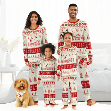 Happy family in matching Coca-Cola Christmas reindeer pajamas with festive red and white patterns, indoors by bed