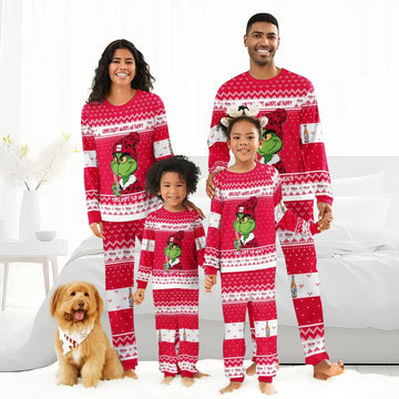 Smiling family of four wearing matching red Grinch and Coors Light holiday pajamas with a small dog indoors