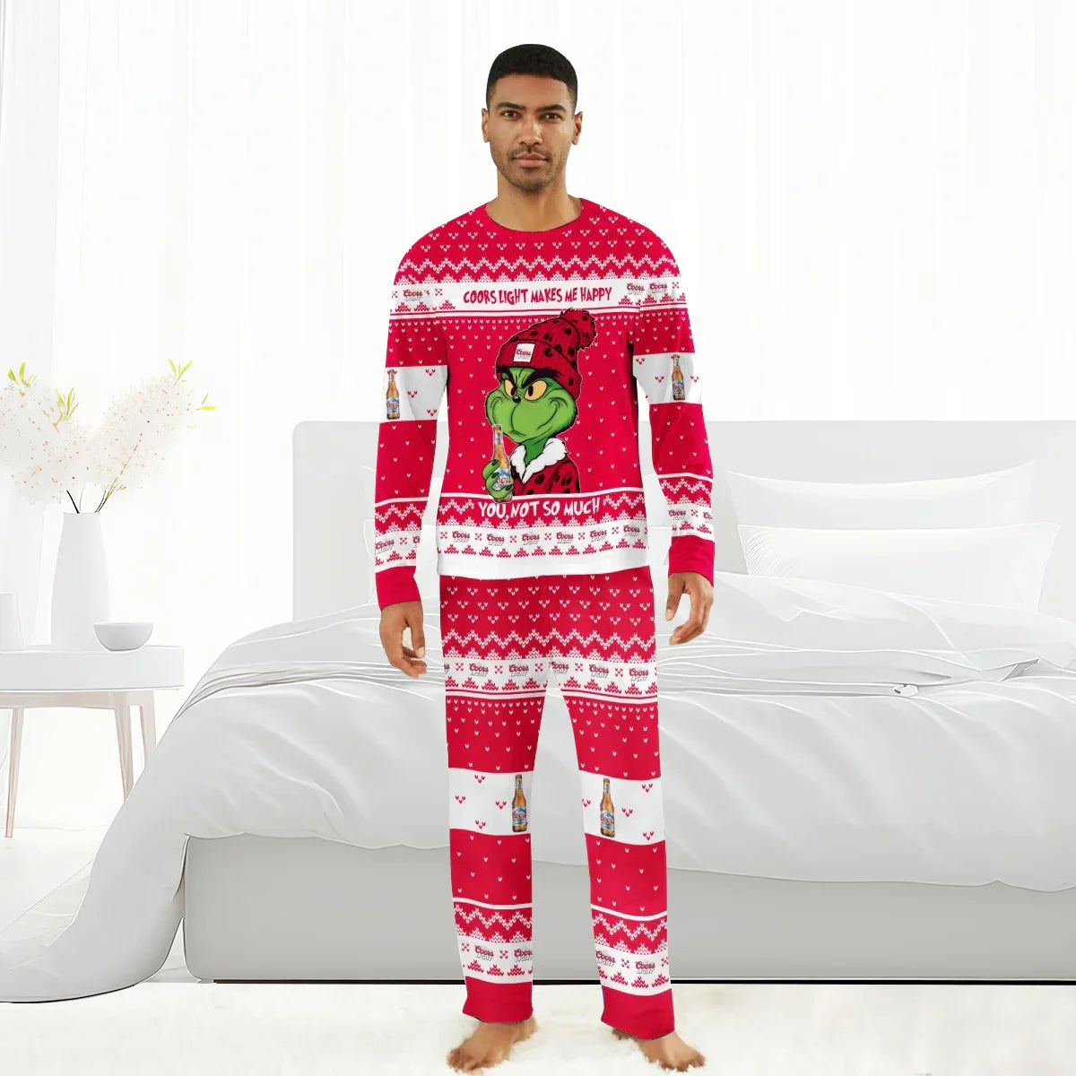Man wearing red Coors Light Grinch Christmas pajamas standing barefoot in a bright bedroom