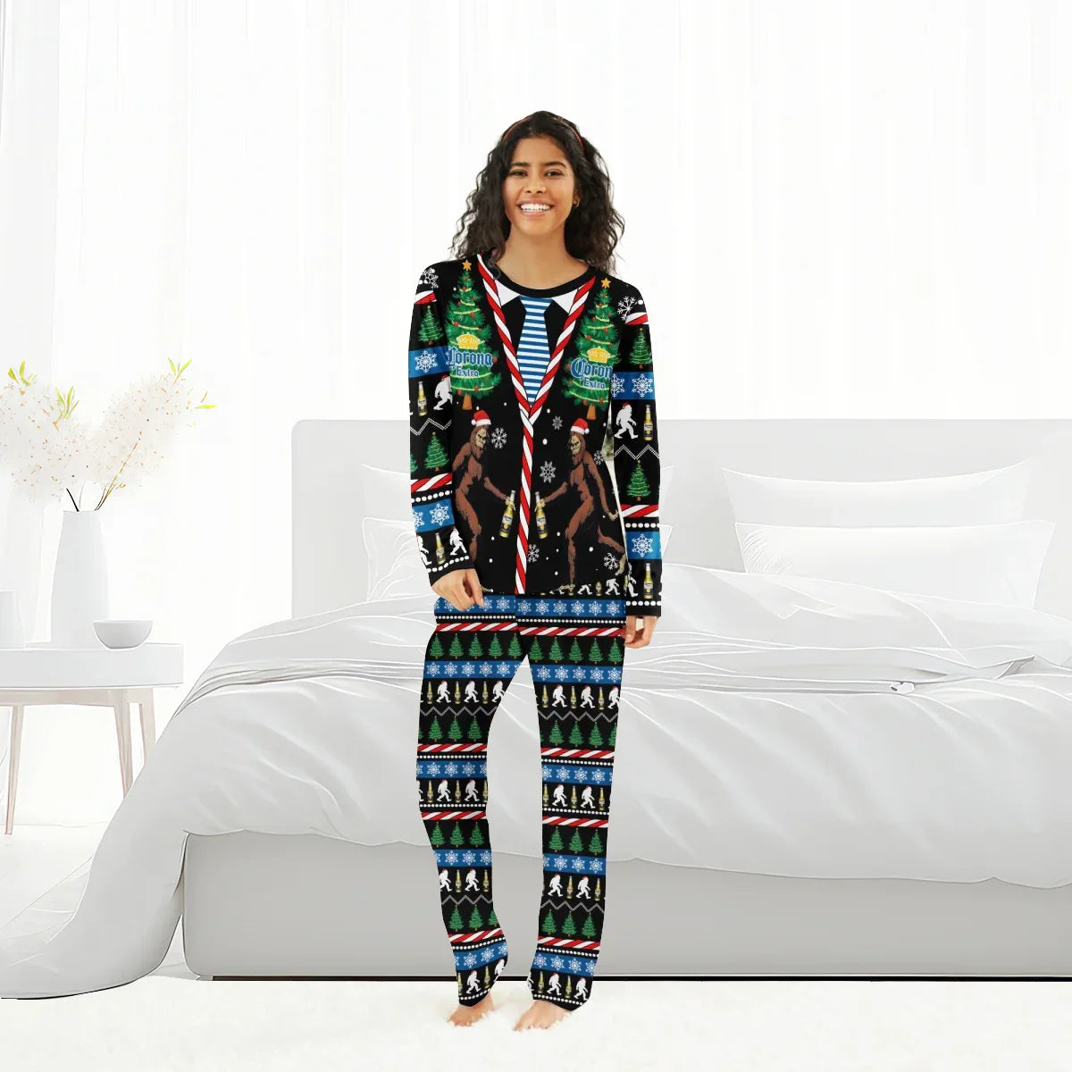 Smiling woman in black Christmas pajamas with Corona Extra, Bigfoot, trees and snowflake patterns in bright bedroom