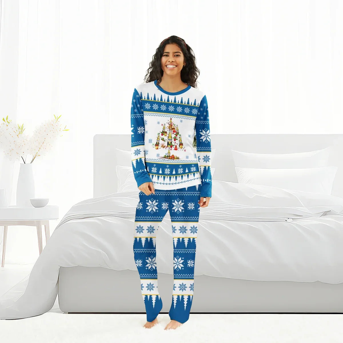 Smiling woman wearing blue and white Christmas tree and snowflake pajama set in bright bedroom