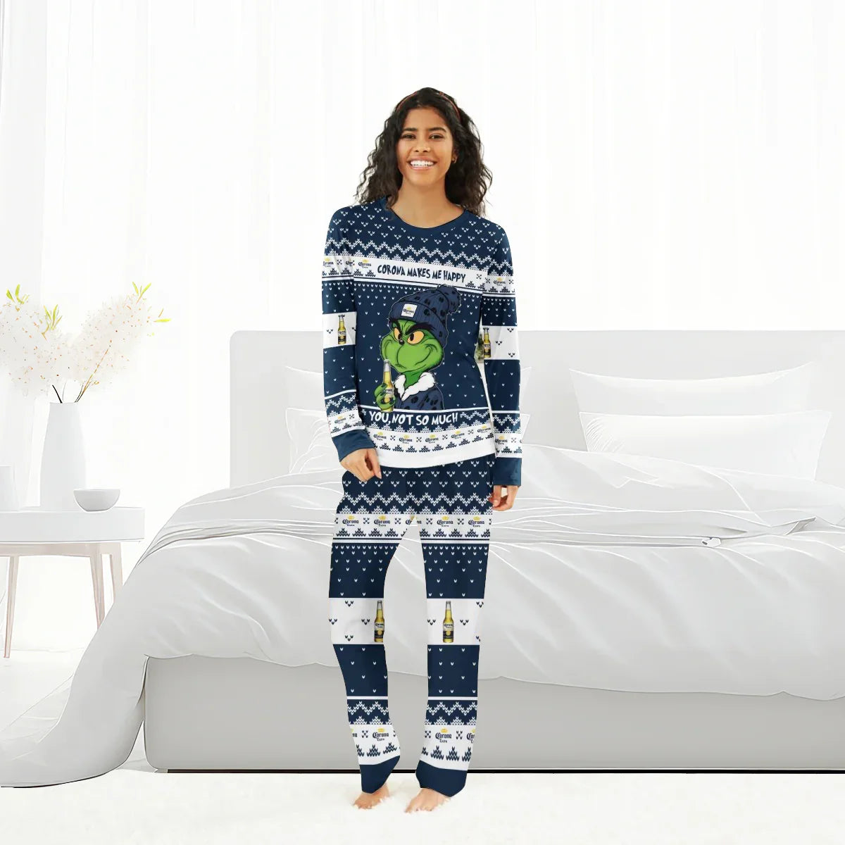 Smiling woman in navy blue Christmas pajamas with Grinch and Corona beer design standing in bright bedroom