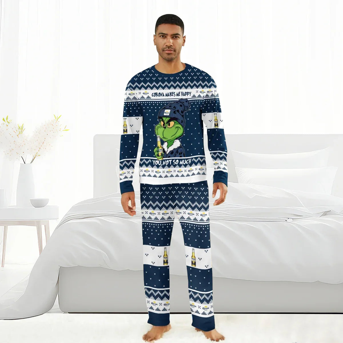 Man wearing navy blue Corona-themed Grinch family pajamas in a bright bedroom with white bed and decor