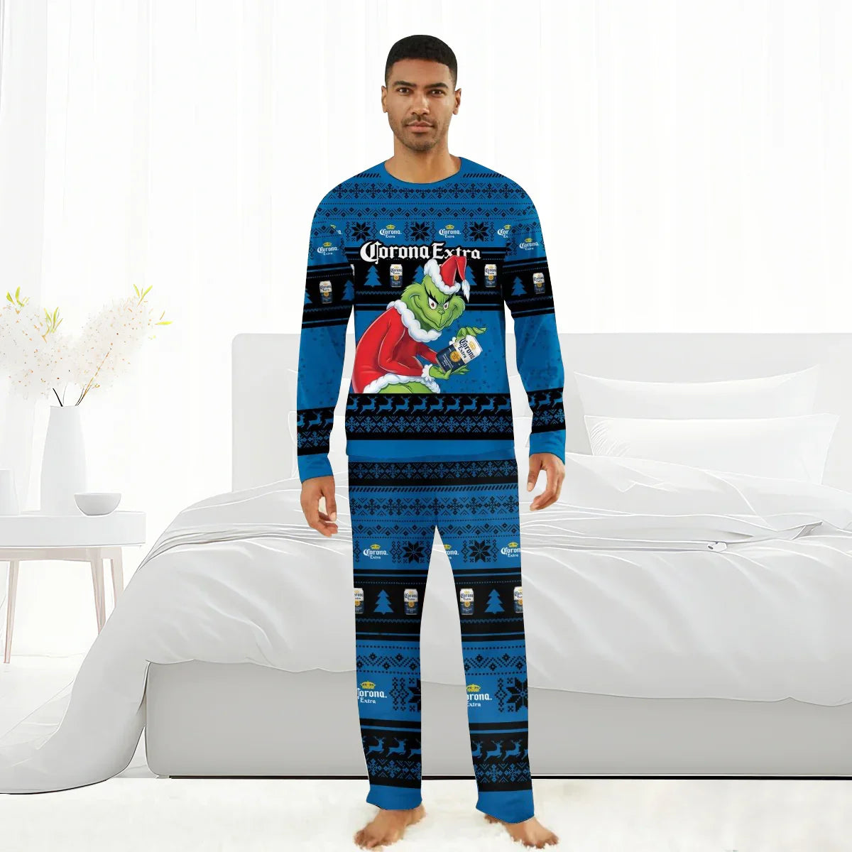 Man wearing blue Christmas pajamas featuring Grinch in Santa suit holding Corona Extra beer, set in bright bedroom