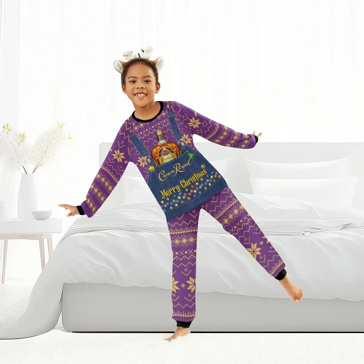 Child wearing purple Crown Royal Merry Christmas pajama set with festive patterns and reindeer headband indoors