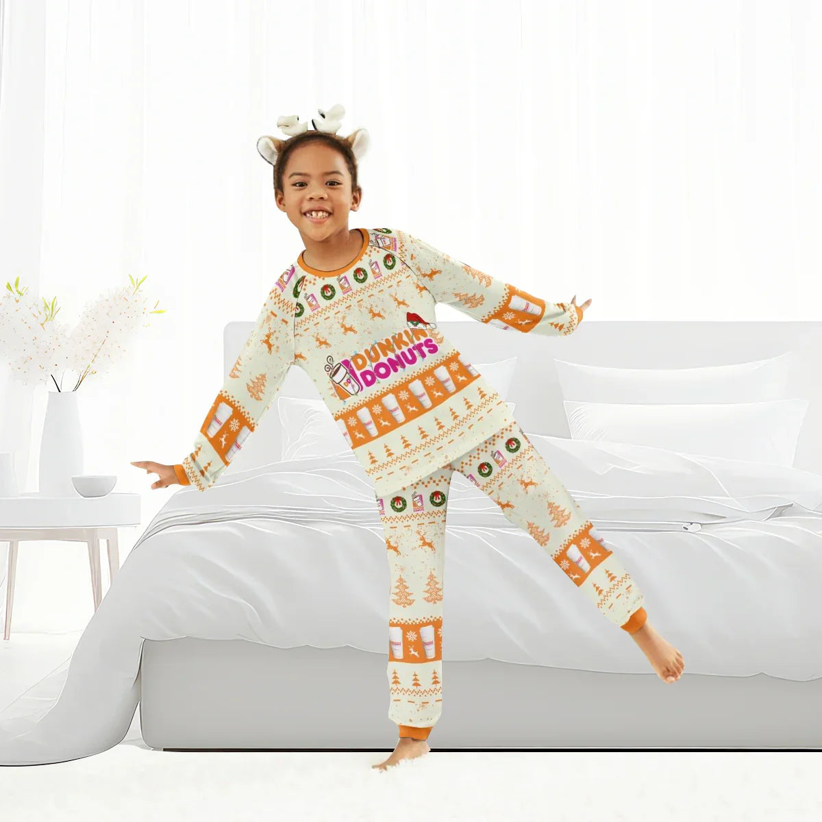 Smiling child wearing Dunkin Donuts Christmas reindeer pajamas in bright bedroom