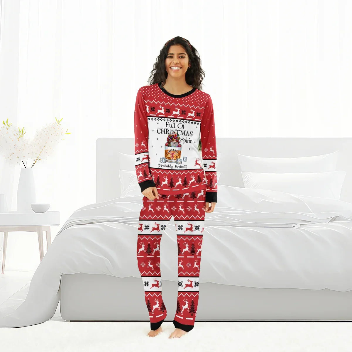 Woman in red Christmas pajamas with reindeer and Fireball whiskey spirit design standing in a bright bedroom