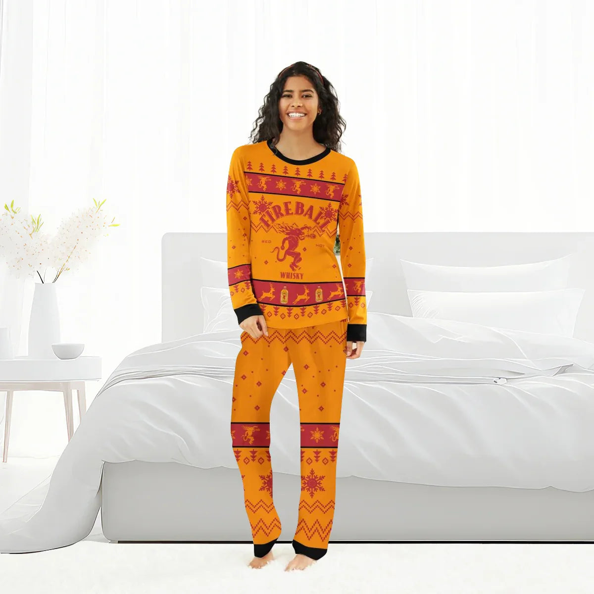 woman in orange Fireball Whisky Christmas pajama set standing in white bedroom