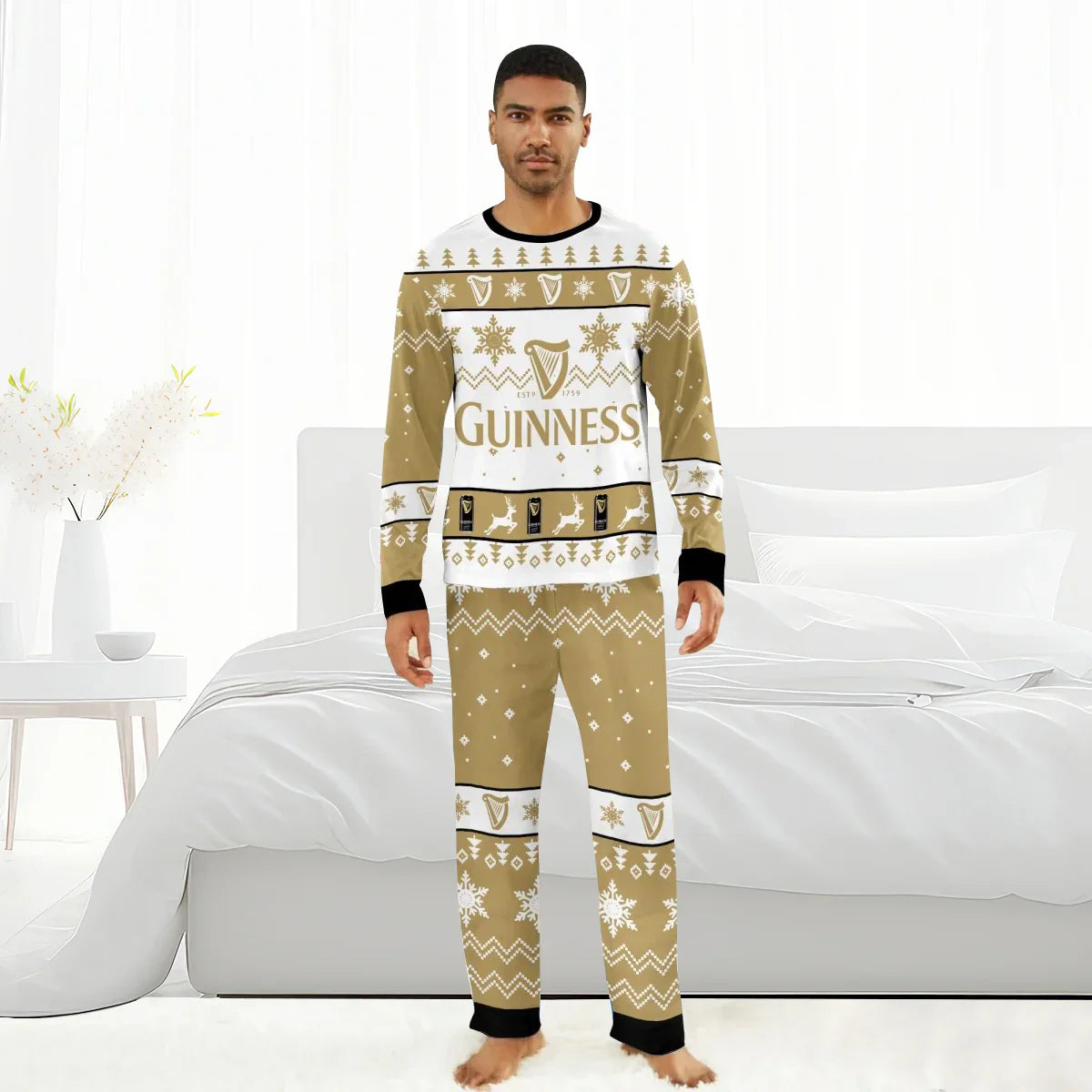 Man wearing beige and white Guinness Christmas holiday pajamas with snowflakes and reindeer, standing barefoot in white bedroom