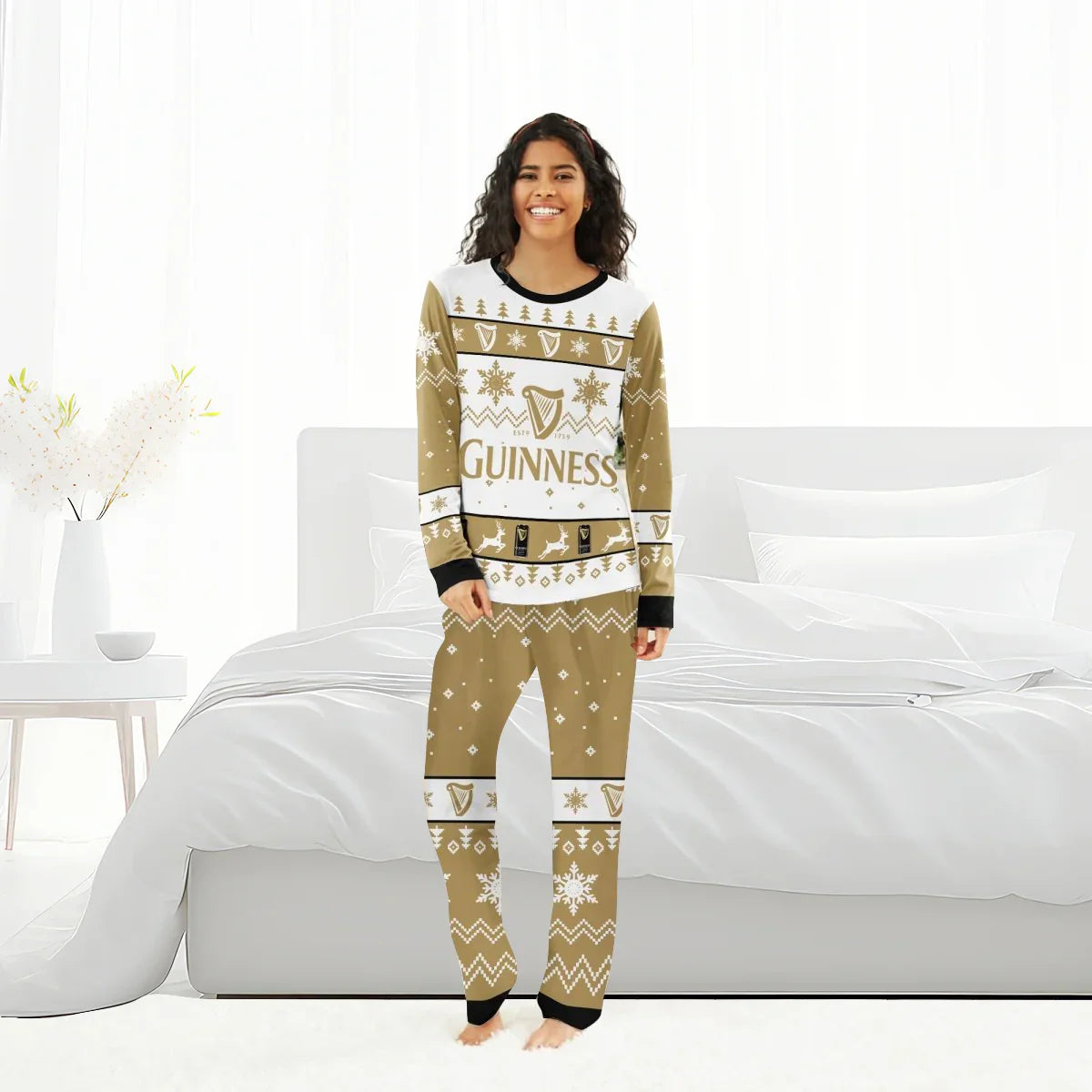 Smiling woman in Guinness holiday pajama set with festive patterns standing in bright white bedroom