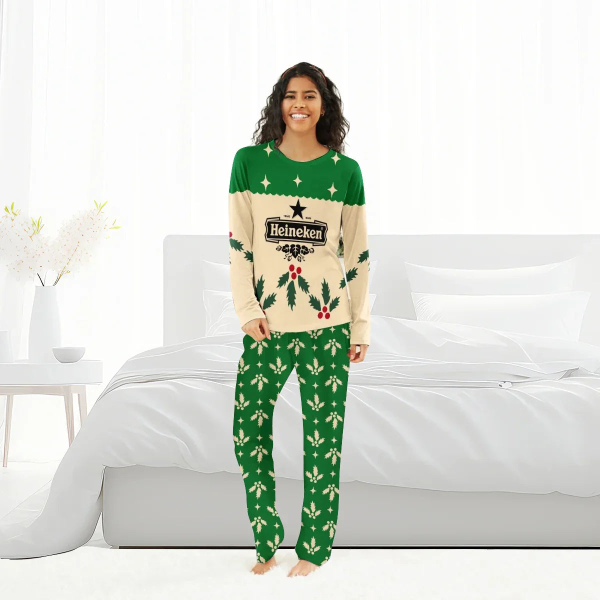 Woman in Heineken Christmas cherry-themed green and beige holiday pajamas standing in a white bedroom