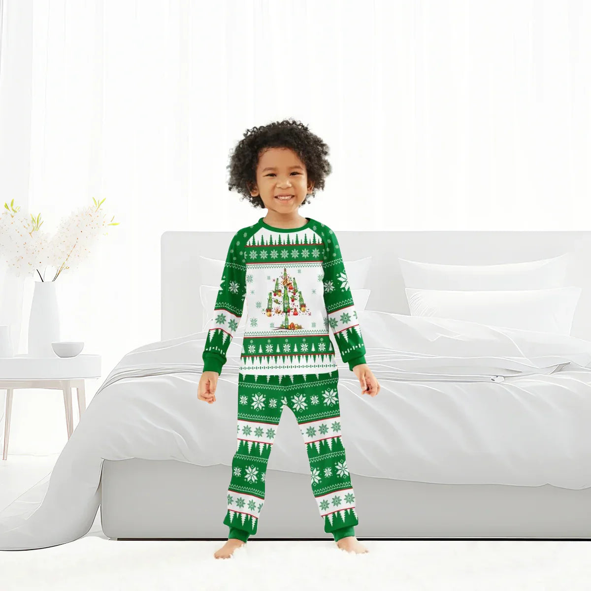 Smiling child in green and white Christmas tree themed holiday pajamas standing in bright bedroom