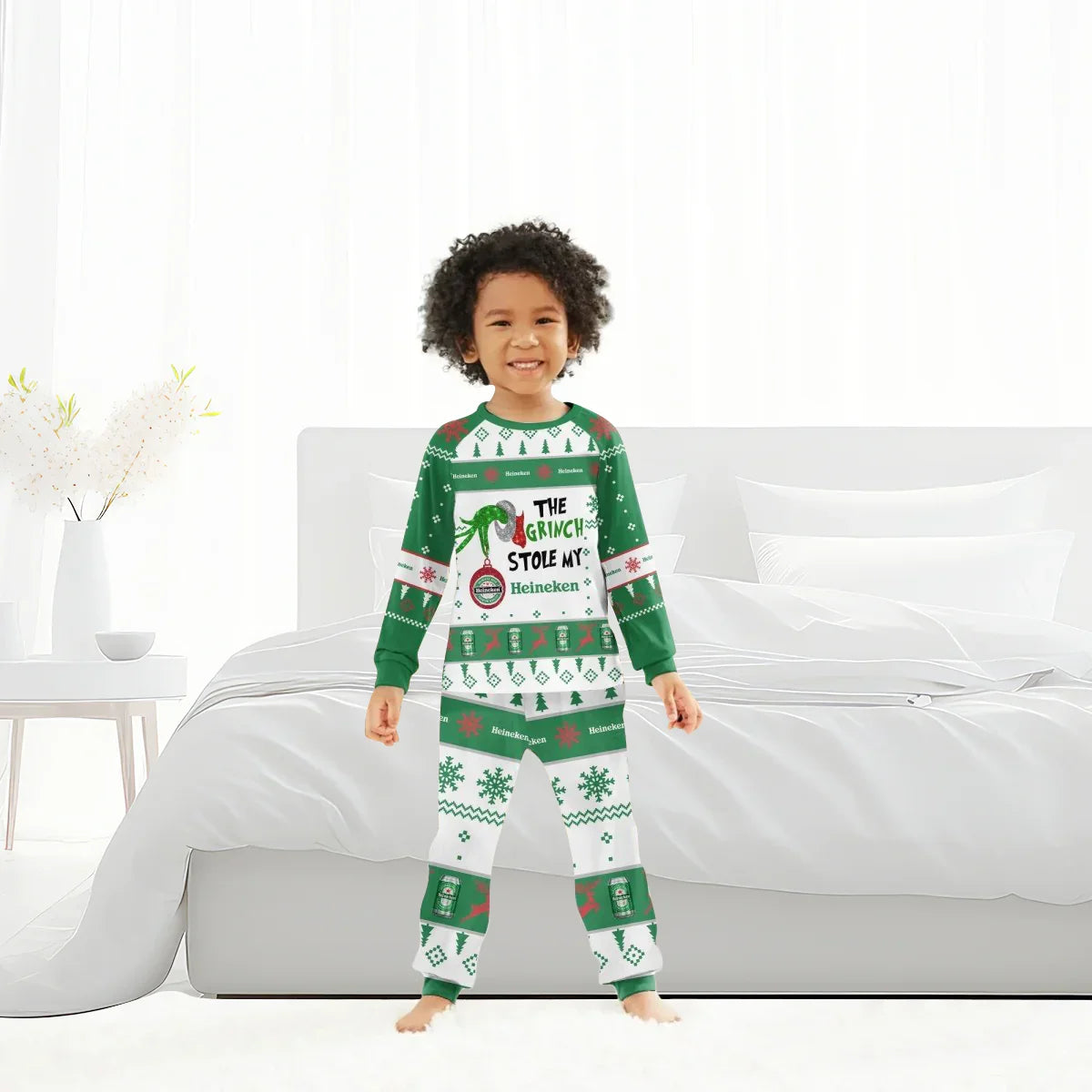Smiling child wearing green and white Christmas pajamas with The Grinch and Heineken design