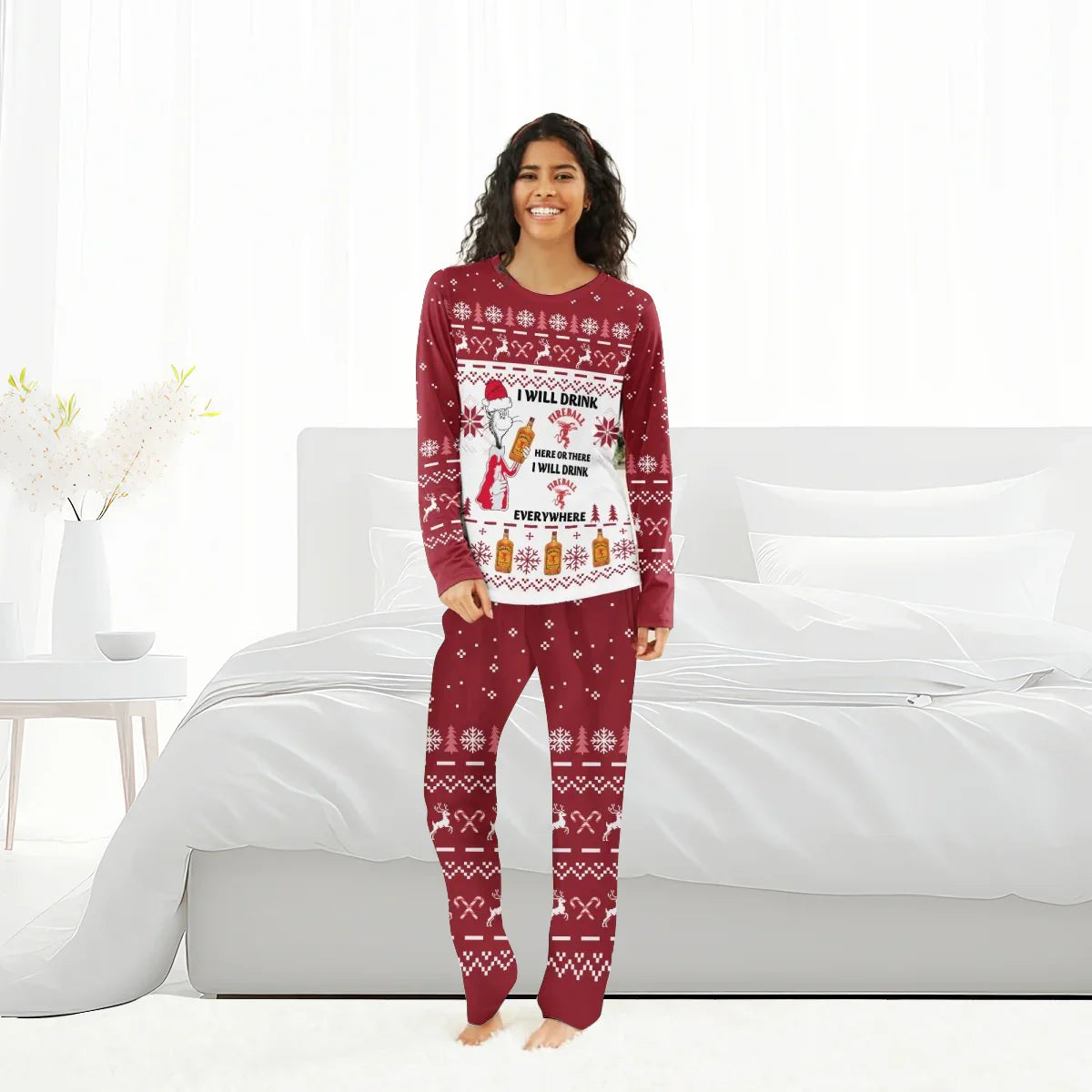 Smiling woman wearing red Christmas family pajamas with Fireball whiskey holiday design in bedroom