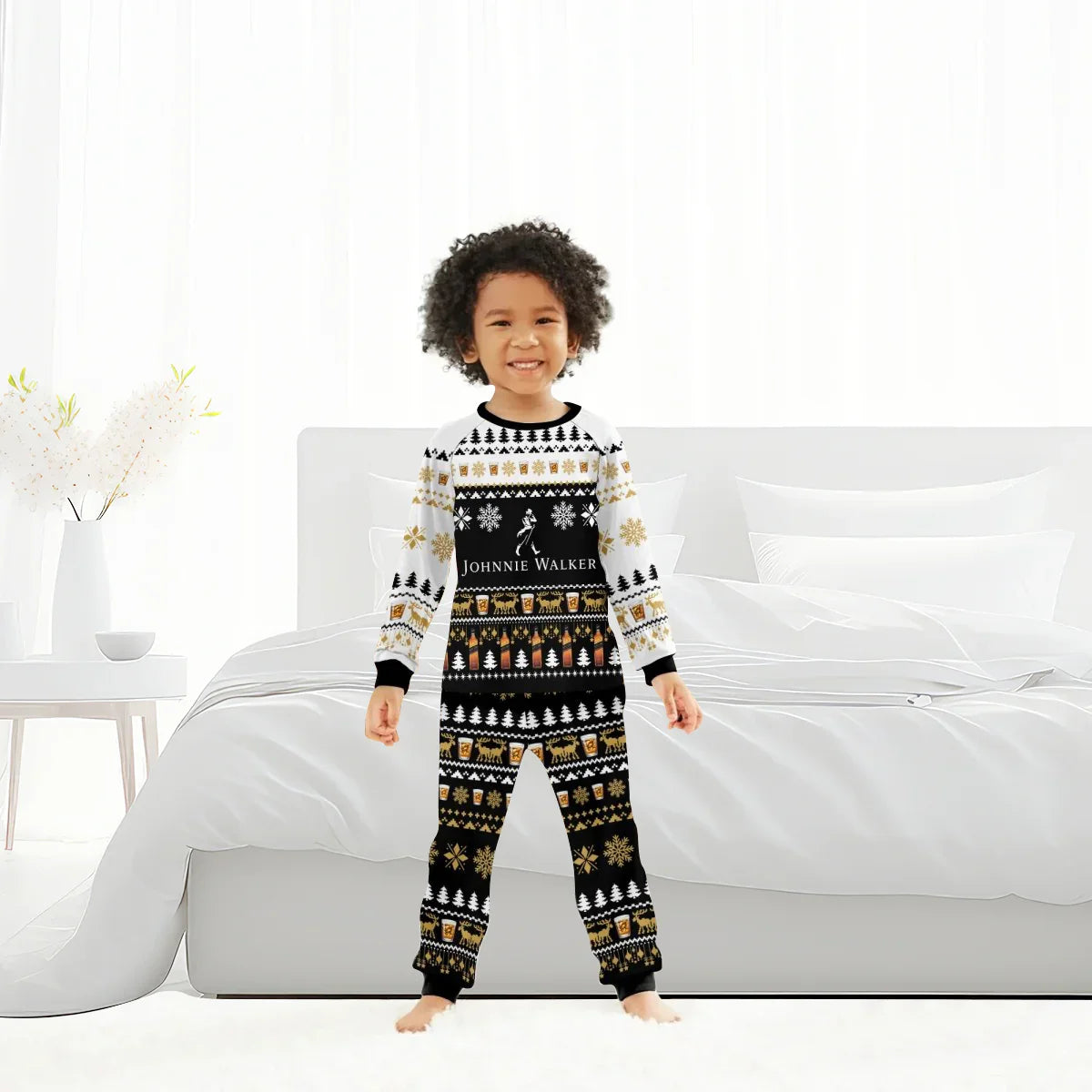 Smiling child in black, white, and gold Johnnie Walker Christmas pajamas standing in a bright bedroom