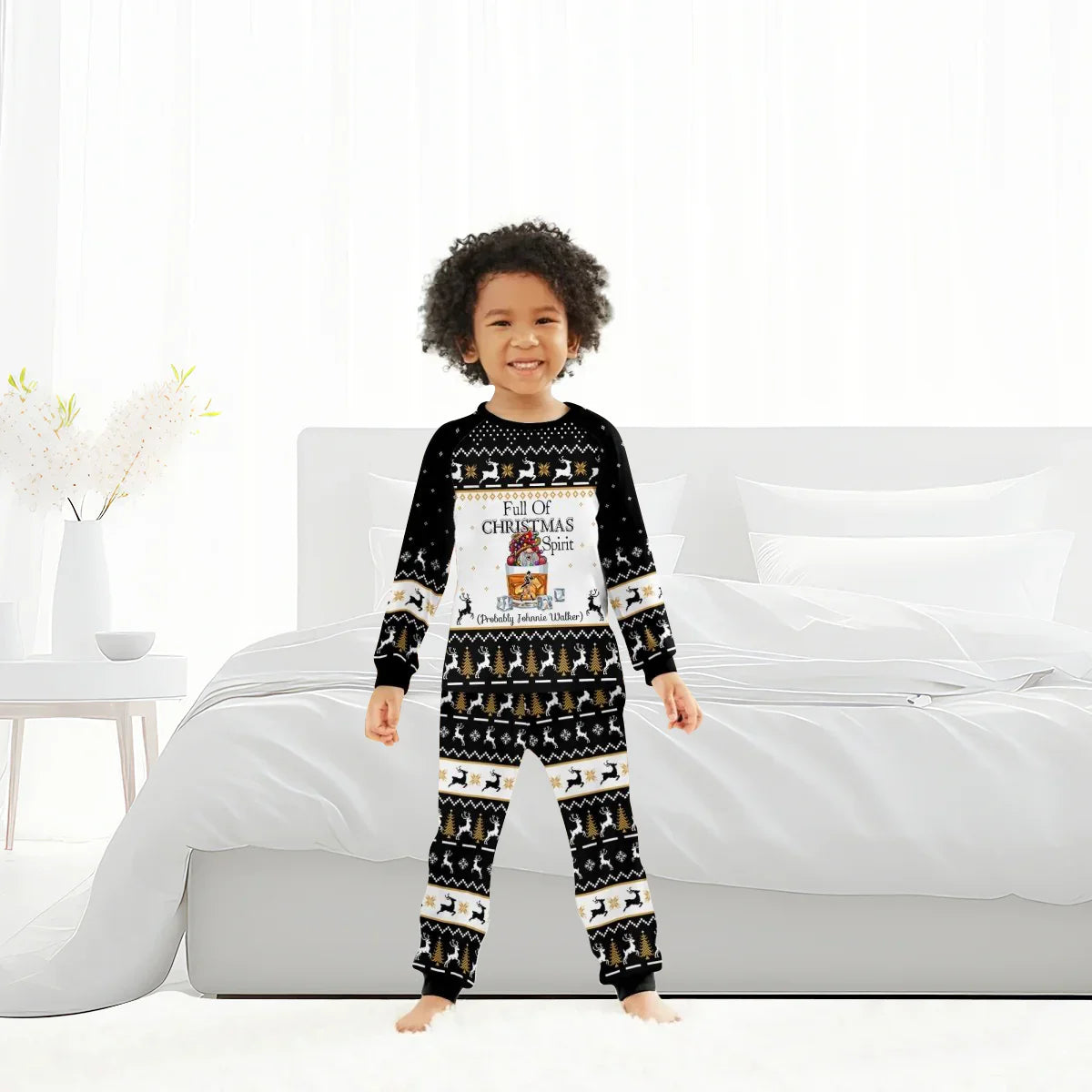 Smiling child in black Christmas pajamas with reindeer and tree pattern, standing in bright bedroom