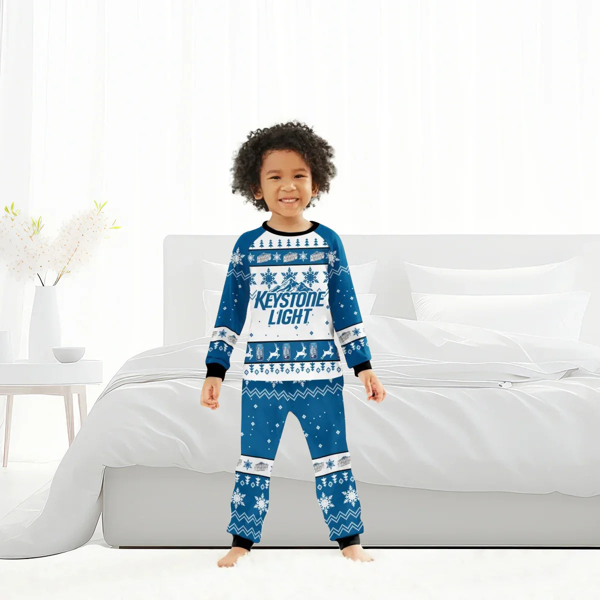 Smiling child in blue and white Keystone Light Christmas pajamas standing barefoot in bright bedroom