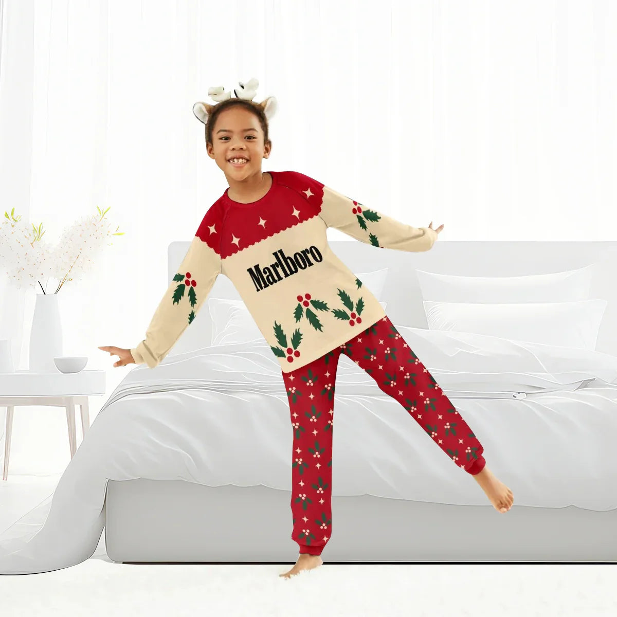 Smiling child in Marlboro Christmas cherry holiday pajamas with reindeer headband in bright bedroom