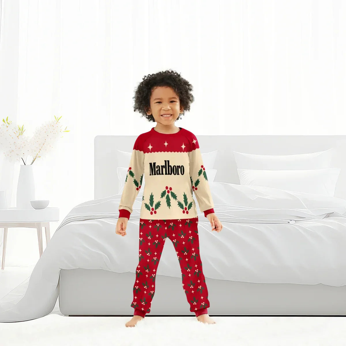 Smiling child in red and beige Marlboro Christmas cherry holiday pajama set standing in bright white bedroom