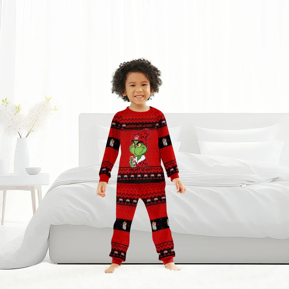 Child wearing red Grinch-themed Marlboro family pajamas in bright modern bedroom