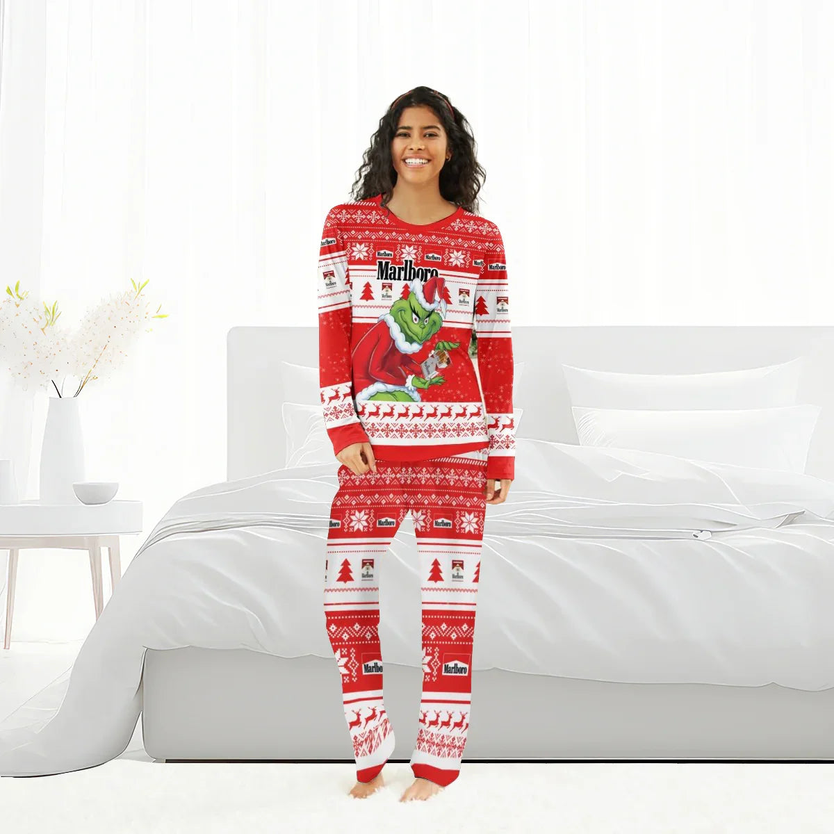 Smiling woman wearing red Marlboro Christmas pajama set with Grinch design standing in bright bedroom