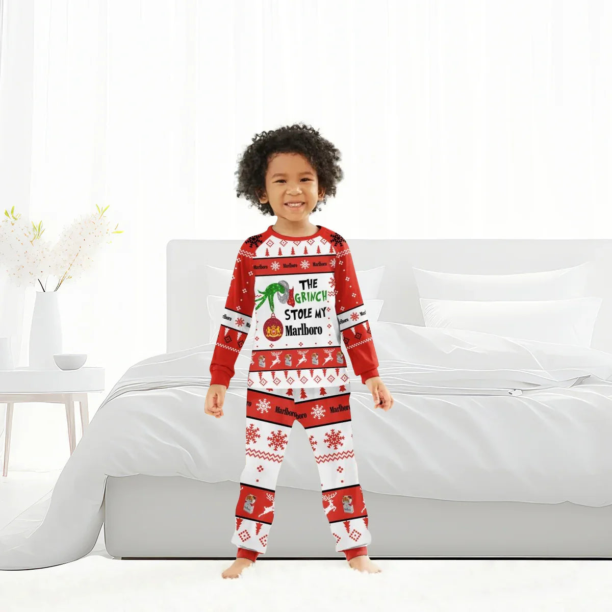 Smiling child wearing red and white Christmas pajamas with Grinch and Marlboro holiday design