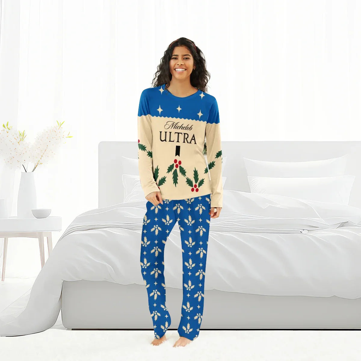Smiling woman wearing blue and beige Michelob Ultra Christmas cherry pajamas in bright bedroom