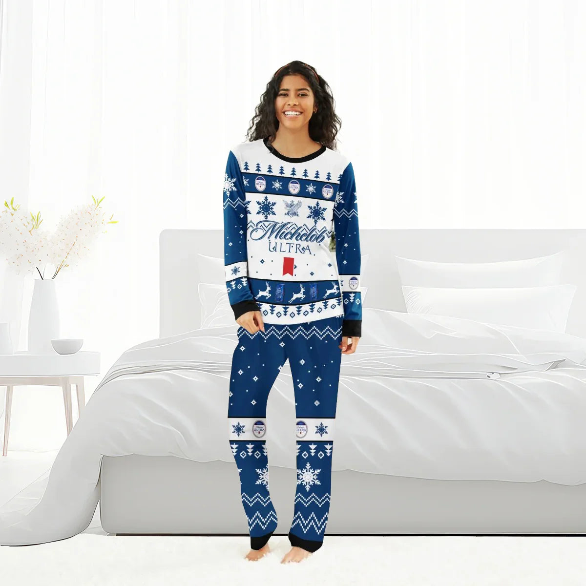 Smiling woman wearing blue and white Michelob Ultra Christmas family pajamas in a bright bedroom