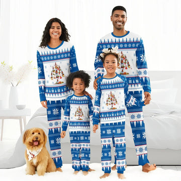 Family of four wearing matching blue and white Christmas tree pajamas with snowflake patterns in a bright living room