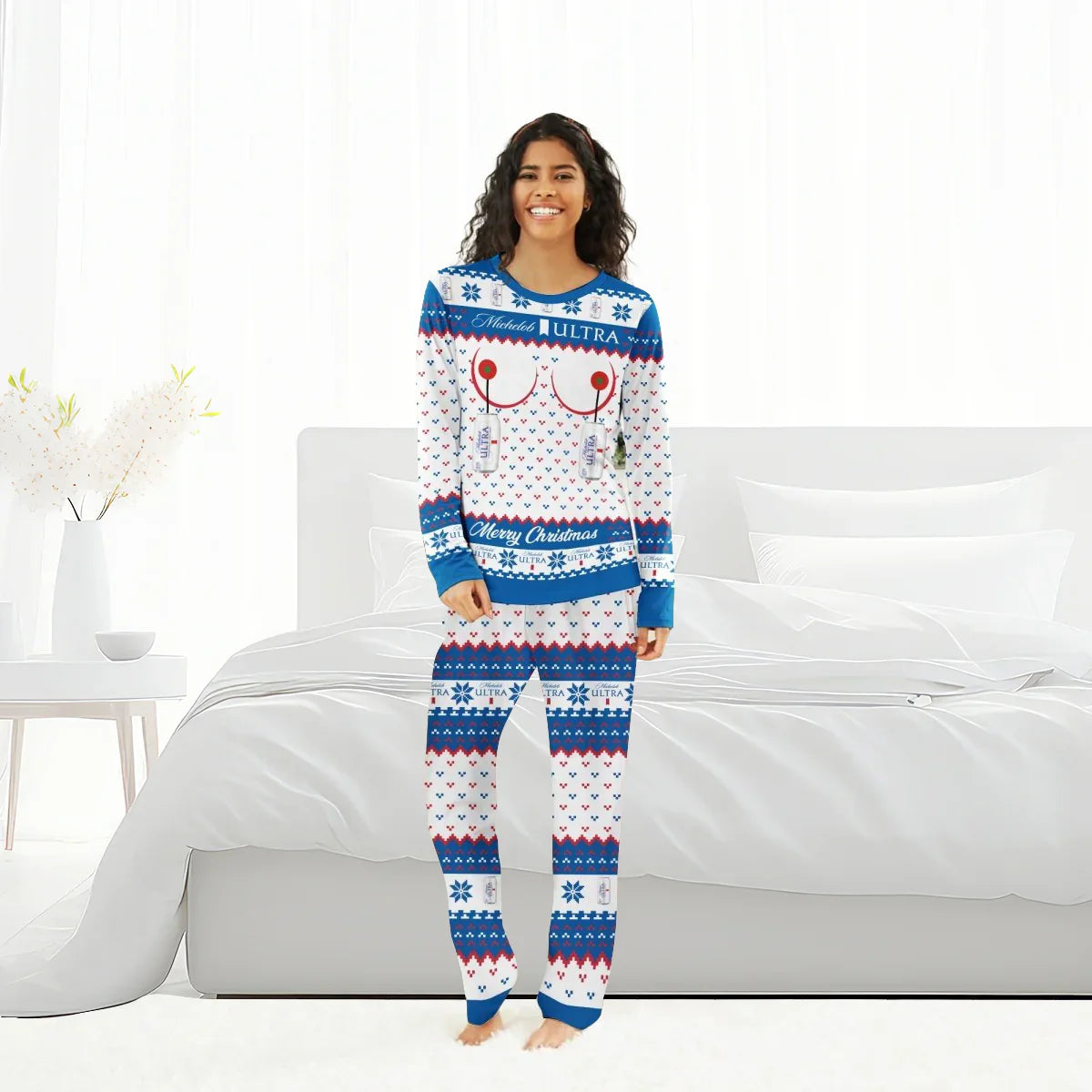 Smiling woman in blue, white, and red Michelob Ultra Merry Christmas family pajamas standing in a bright bedroom