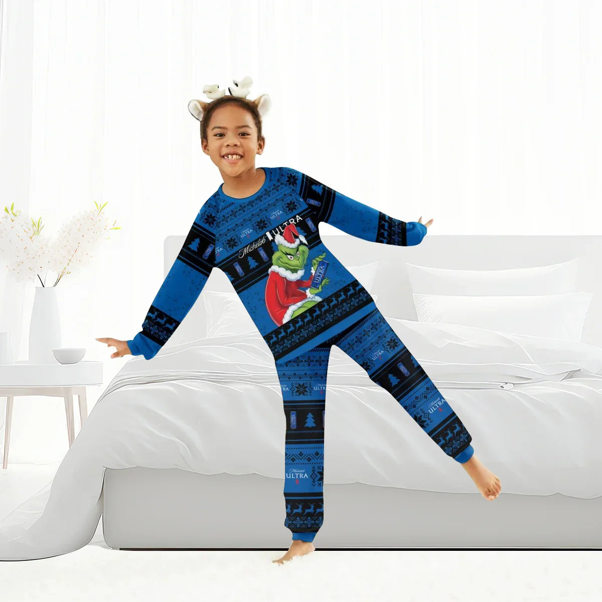 Child in blue holiday onesie with Grinch and Michelob Ultra design, wearing reindeer headband