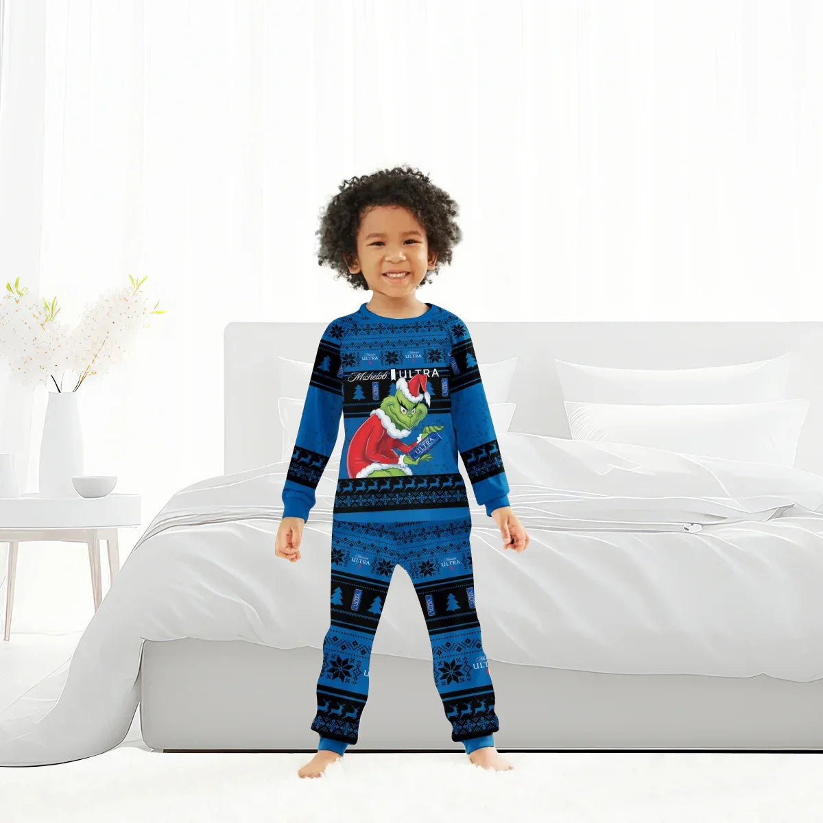 Smiling child in blue Grinch-themed Christmas pajamas standing barefoot in white modern bedroom