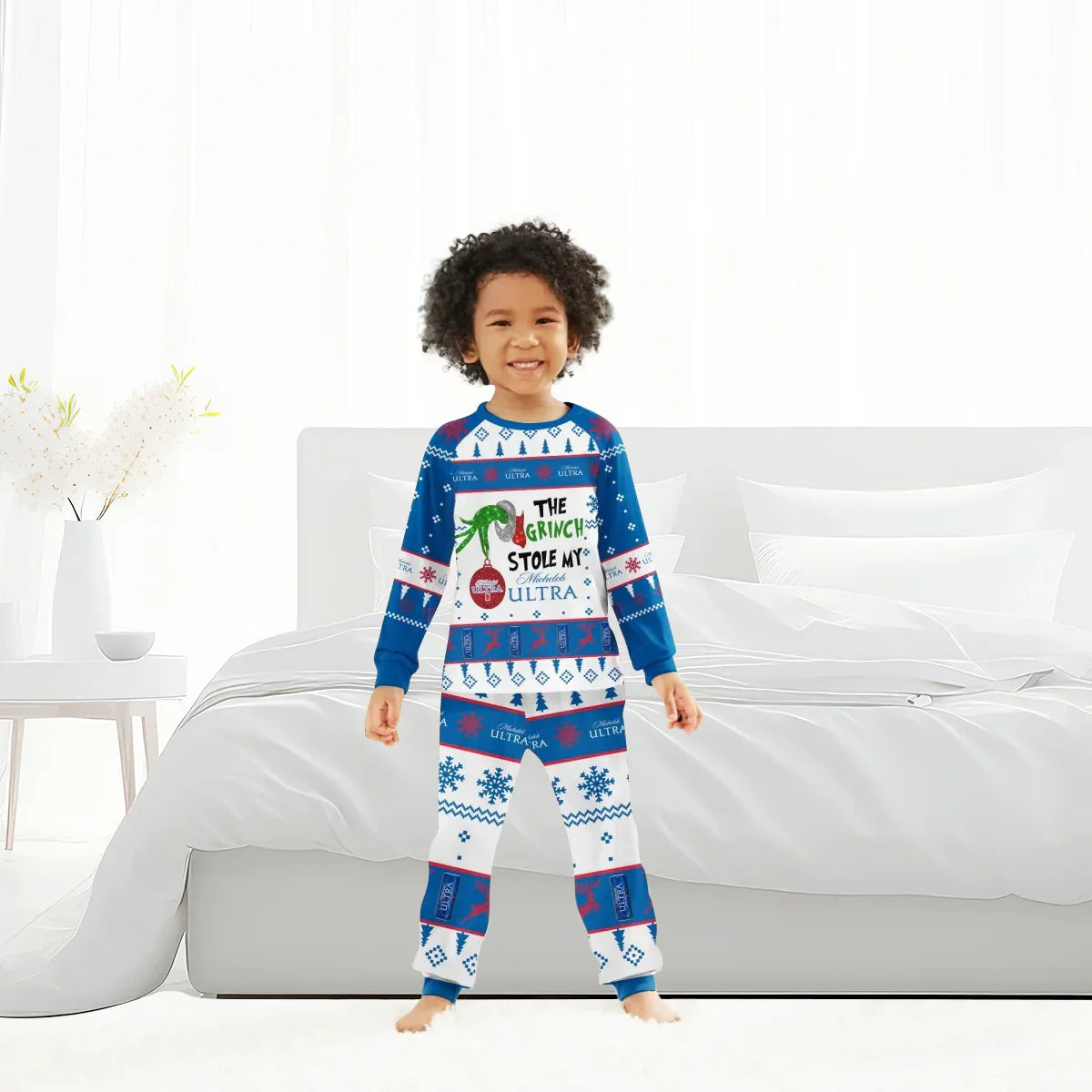 Smiling child in Michelob Ultra Grinch-themed Christmas pajamas standing in bright bedroom