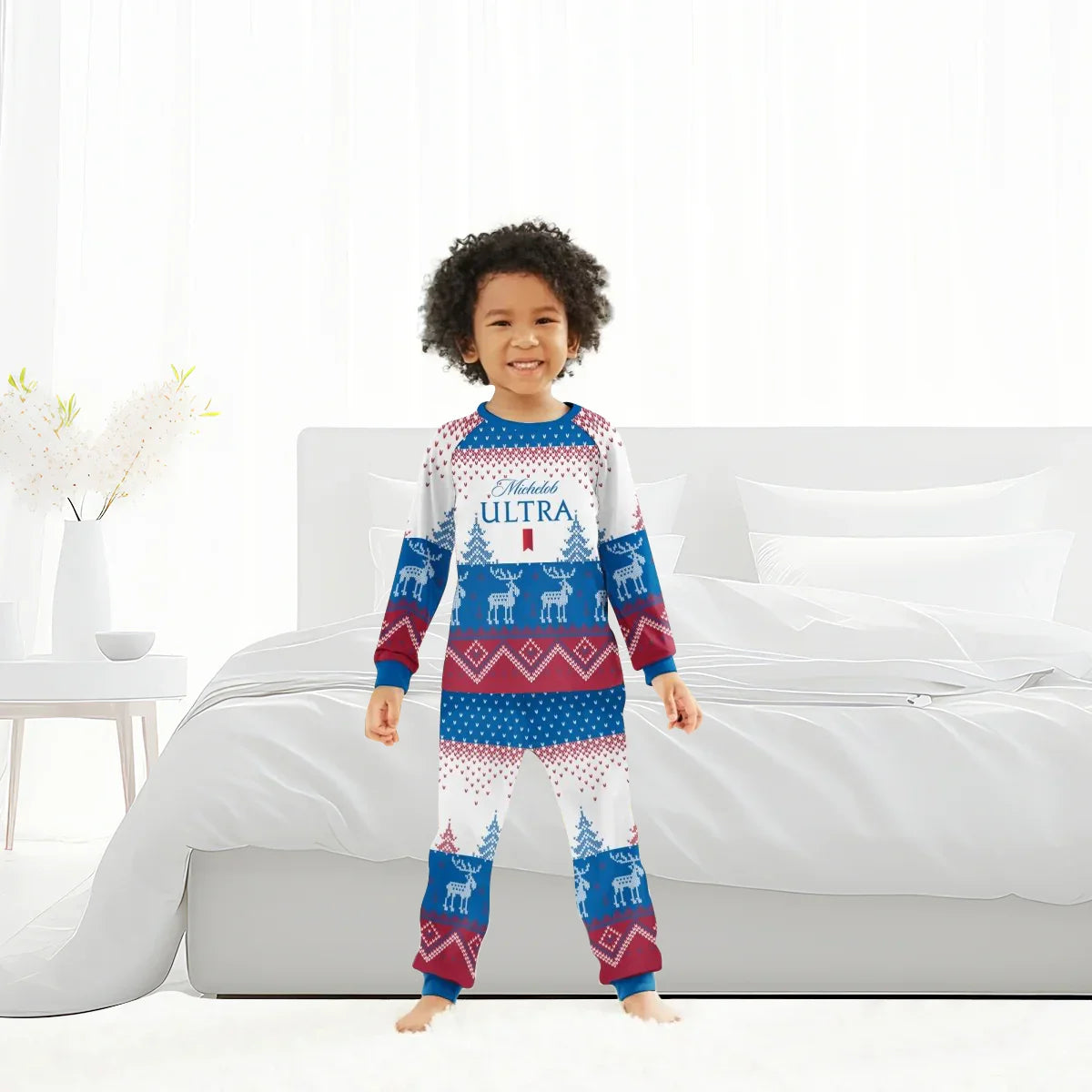 Child wearing Michelob Ultra winter reindeer holiday pajama set in white, blue, and red in bright bedroom