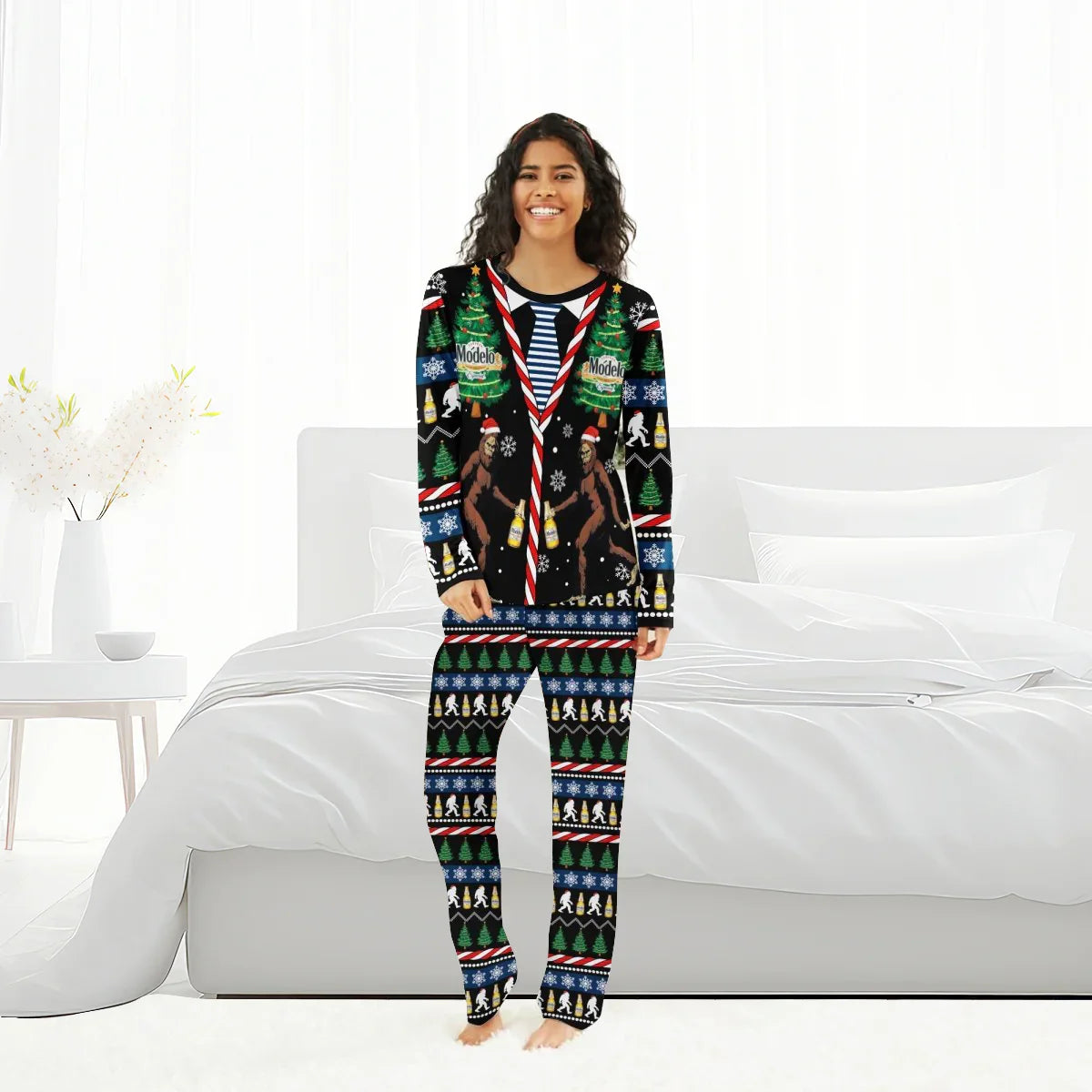 Woman wearing Modelo Christmas Bigfoot family pajamas in a bright bedroom with white bedding