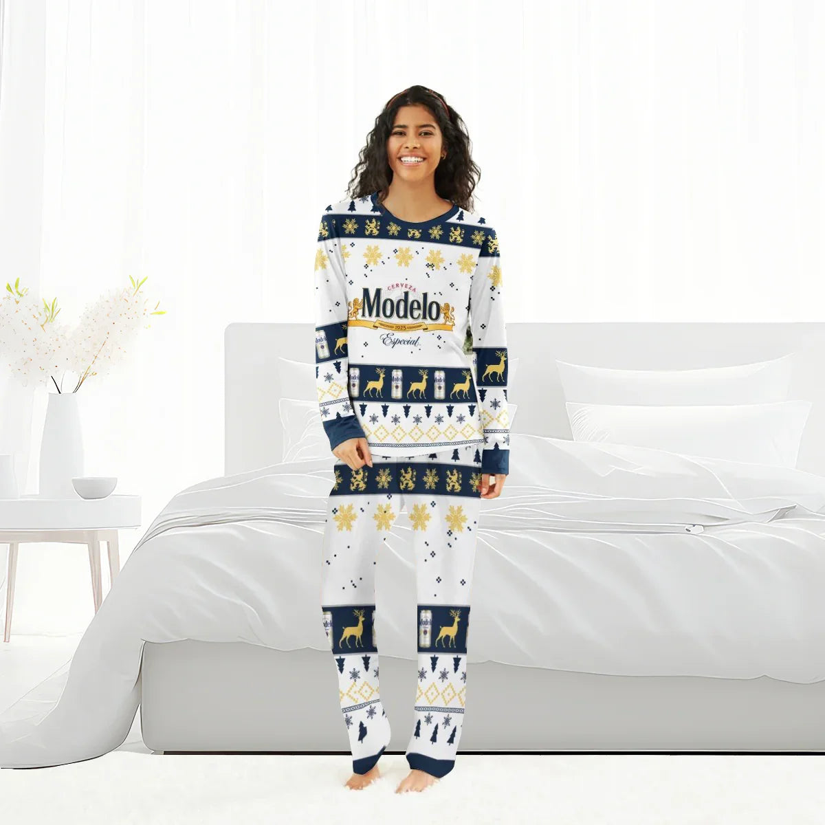 Smiling woman wearing white Modelo Christmas holiday family pajamas with reindeer and snowflake patterns in modern bedroom