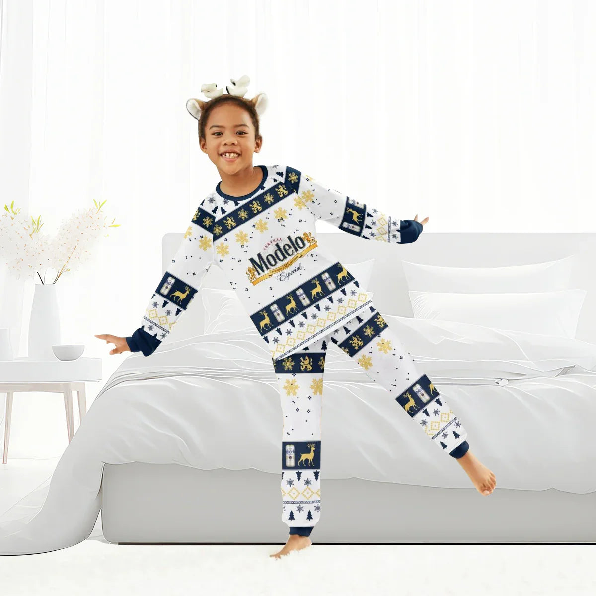Smiling child wearing Modelo Christmas holiday pajamas with reindeer headband in bright bedroom