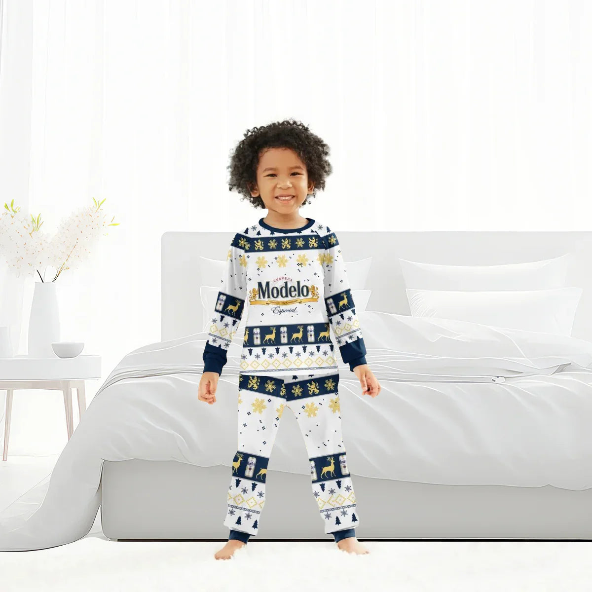 Smiling child in white and navy Modelo Especial holiday pajamas with gold accents, standing in bright bedroom